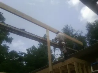 Carpenter setting a ridge beam over a new addition frame — Ice Dam Removal by Roofing Brothers in West Baldwin