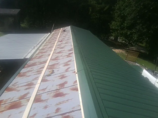 Old rusted panels beside newly installed green metal roofing — Wind Damage Roof Repair by Roofing Brothers in West Baldwin