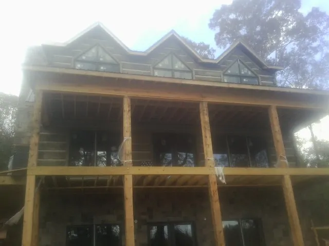 Dormers and porch framing on a large log home under construction — Roof Coating work by our crew in West Baldwin