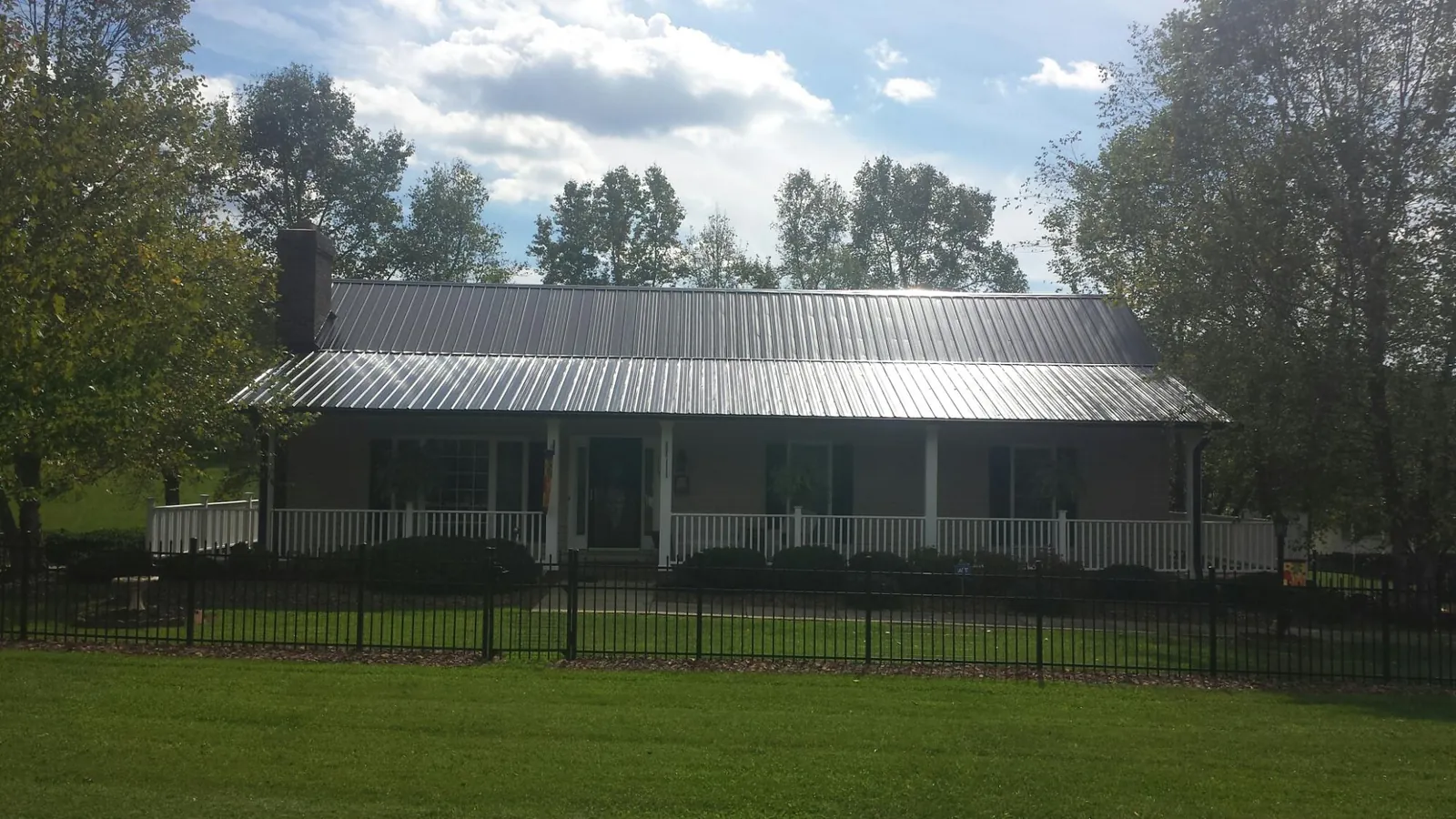 Gray metal roof on a brick ranch with a full width front porch — Gutter Guard Installation work by our crew in West Baldwin