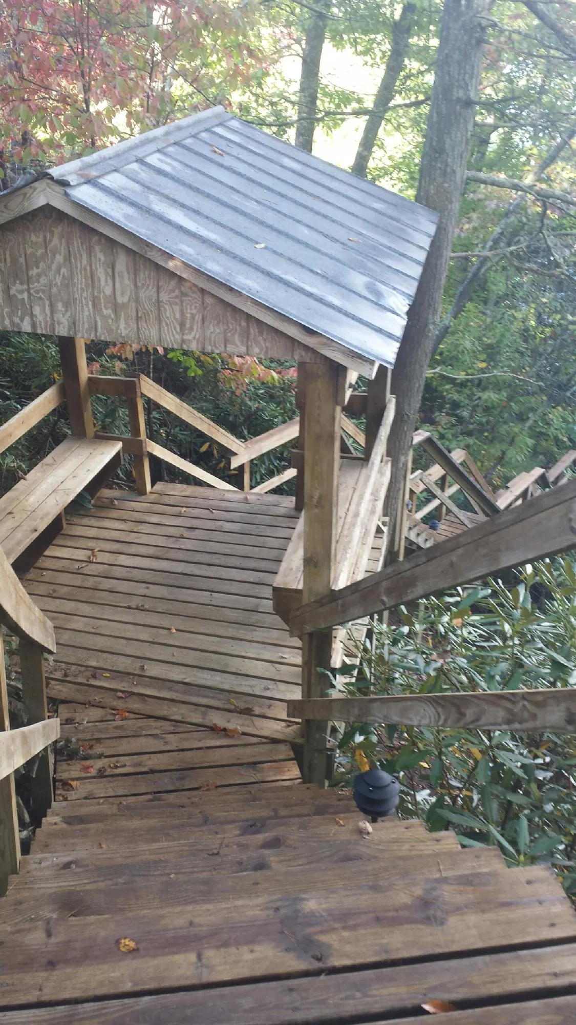 Metal roofed shelter over wooden steps on a wooded walkway — Skylight Repair & Installation work by our crew in West Baldwin