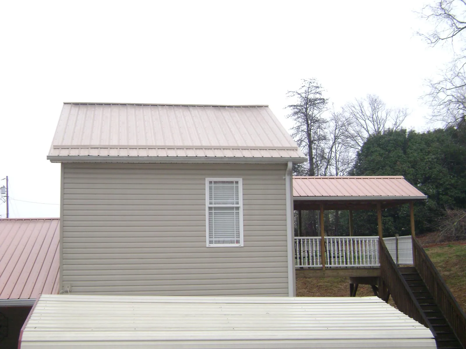 Tan metal roofs on a two story addition and attached porch, from a Roof Replacement job in West Baldwin