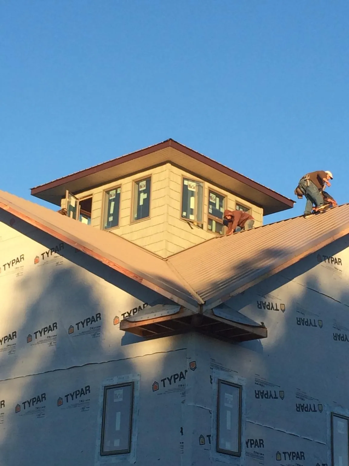 Roofers working around a rooftop cupola on a new metal roof at sunset — Roof Waterproofing in West Baldwin by Roofing Brothers